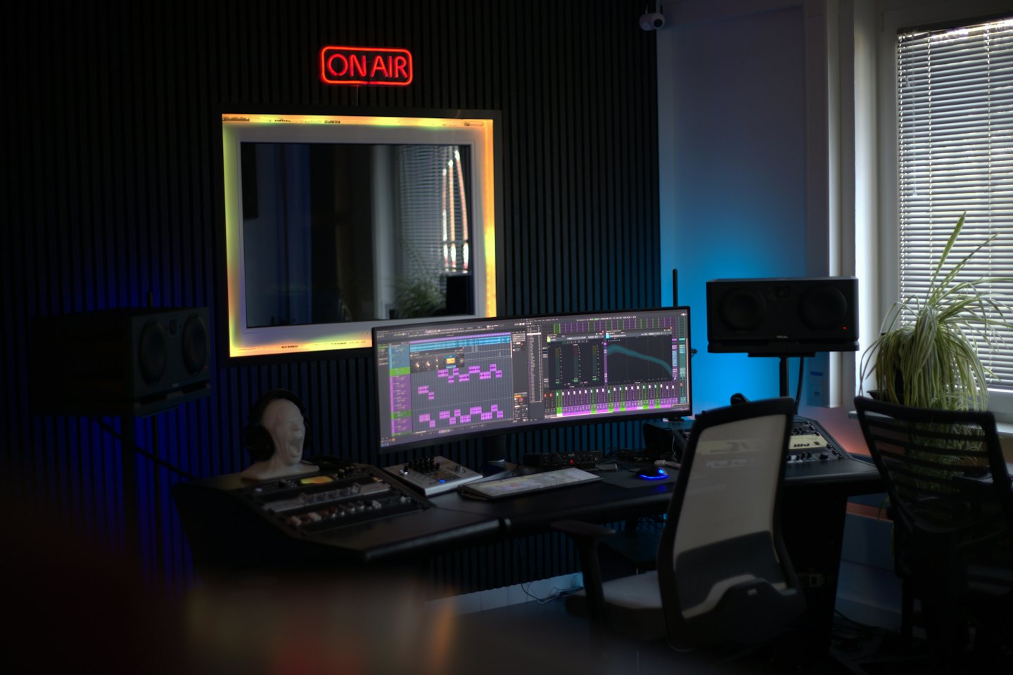 Music production studio with ultrawide monitor and mixing console.
