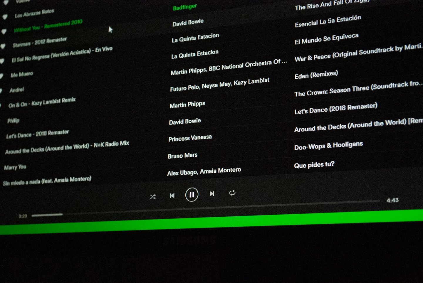 Computer screen displays a digital music playlist with song titles and artist names.