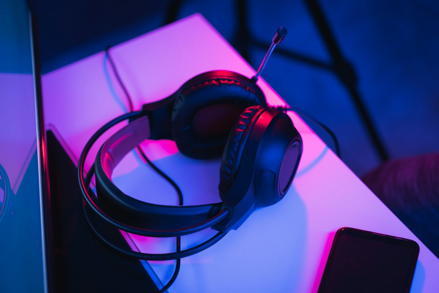 Black gaming headphones and dark smartphone on white surface.